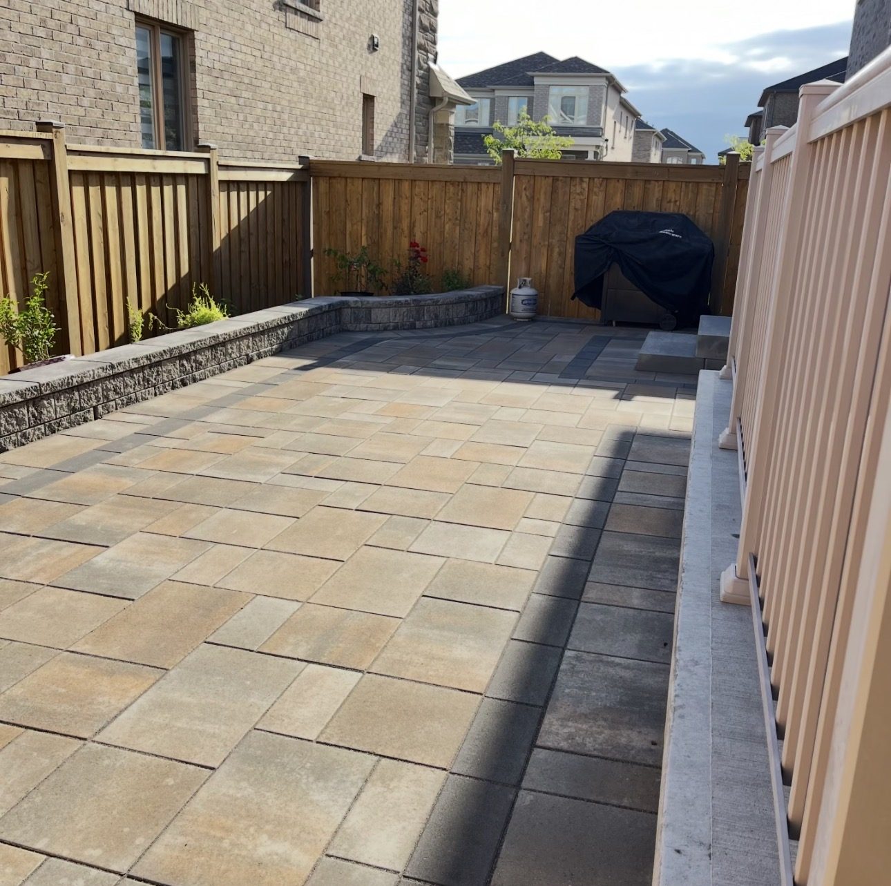 Sand-tone interlock patio in a Markham backyard with a stone planter wall and built-in grill nook