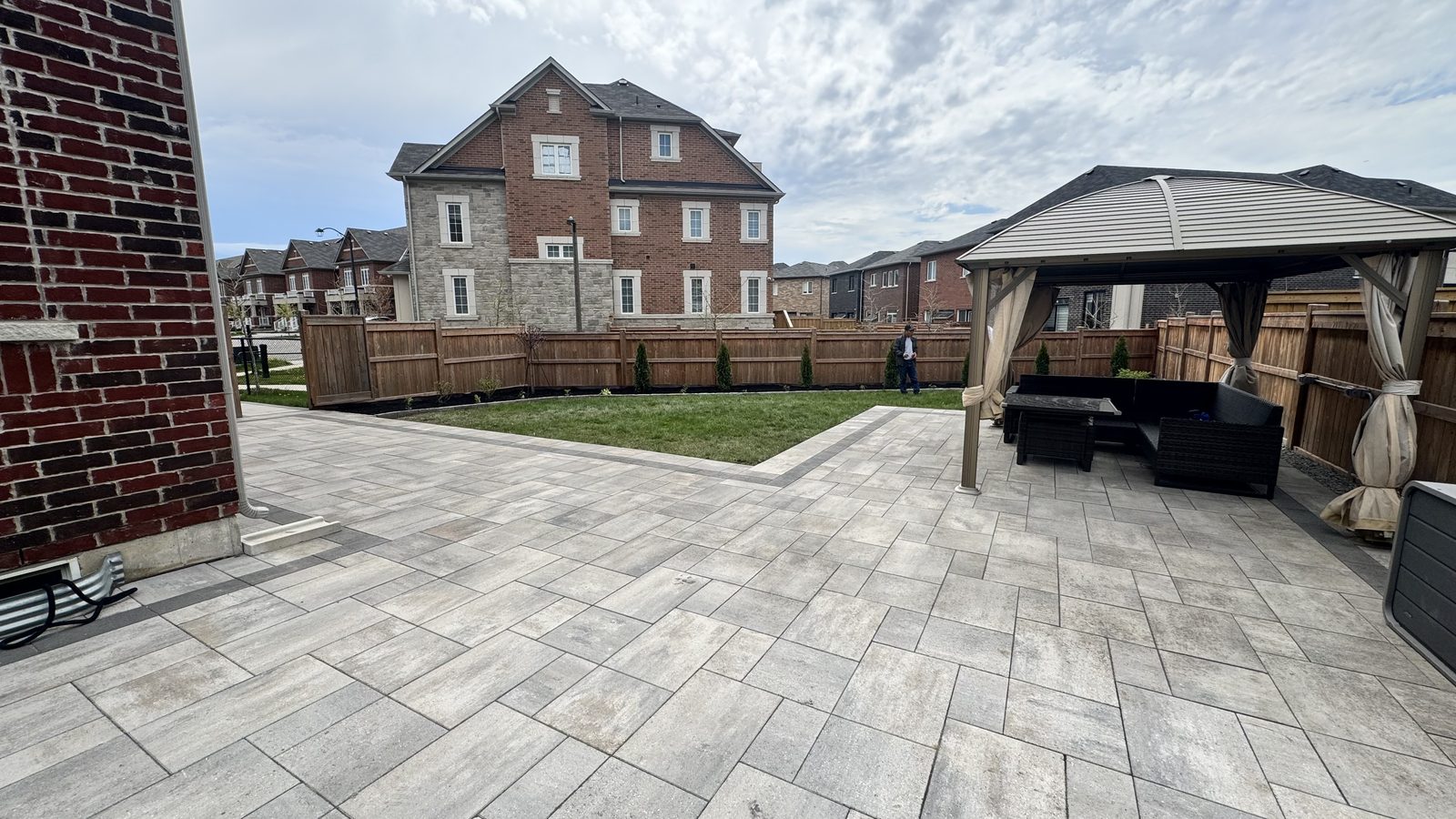 Wide-format silver paver patio in a Richmond Hill backyard with gazebo, lounge furniture, and a soft lawn opening